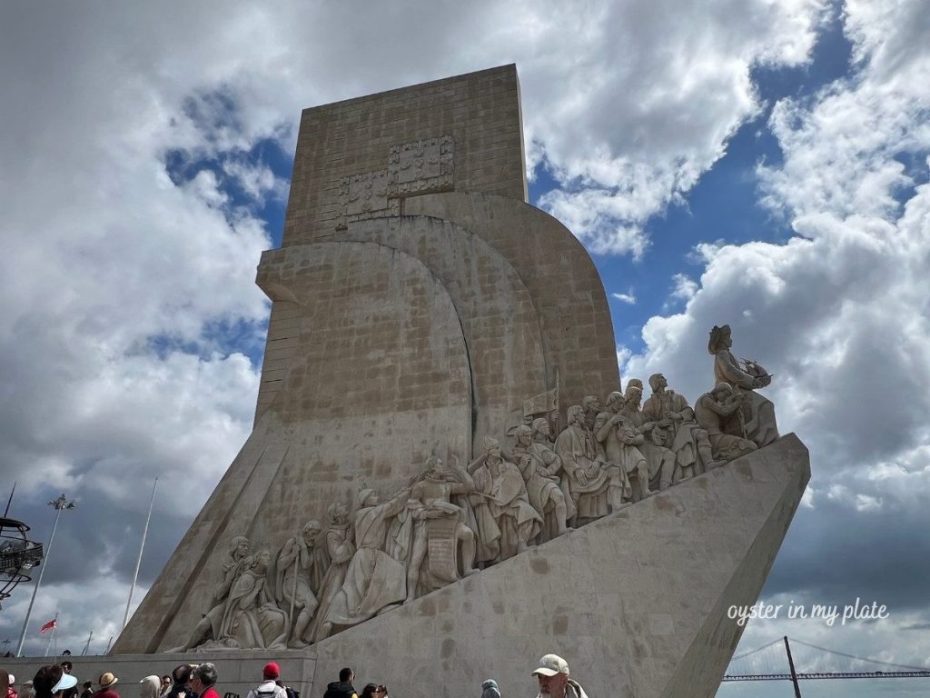 Monument to the Discoveries (Padrão dos Descobrimentos) in Lisbon, a tall stone monument with statues of Portuguese explorers on a cloudy day