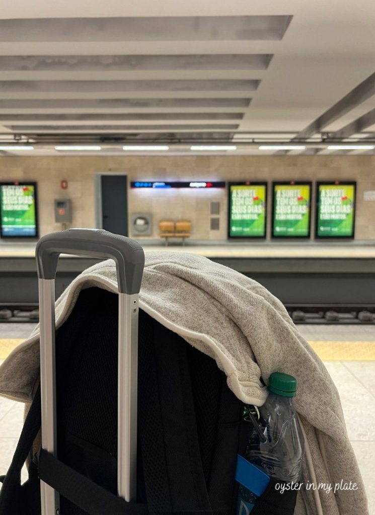 리스본 공항 지하철역 플랫폼에서 캐리어를 앞에 놓고 플랫폼을 바라보며 대기 중인 모습